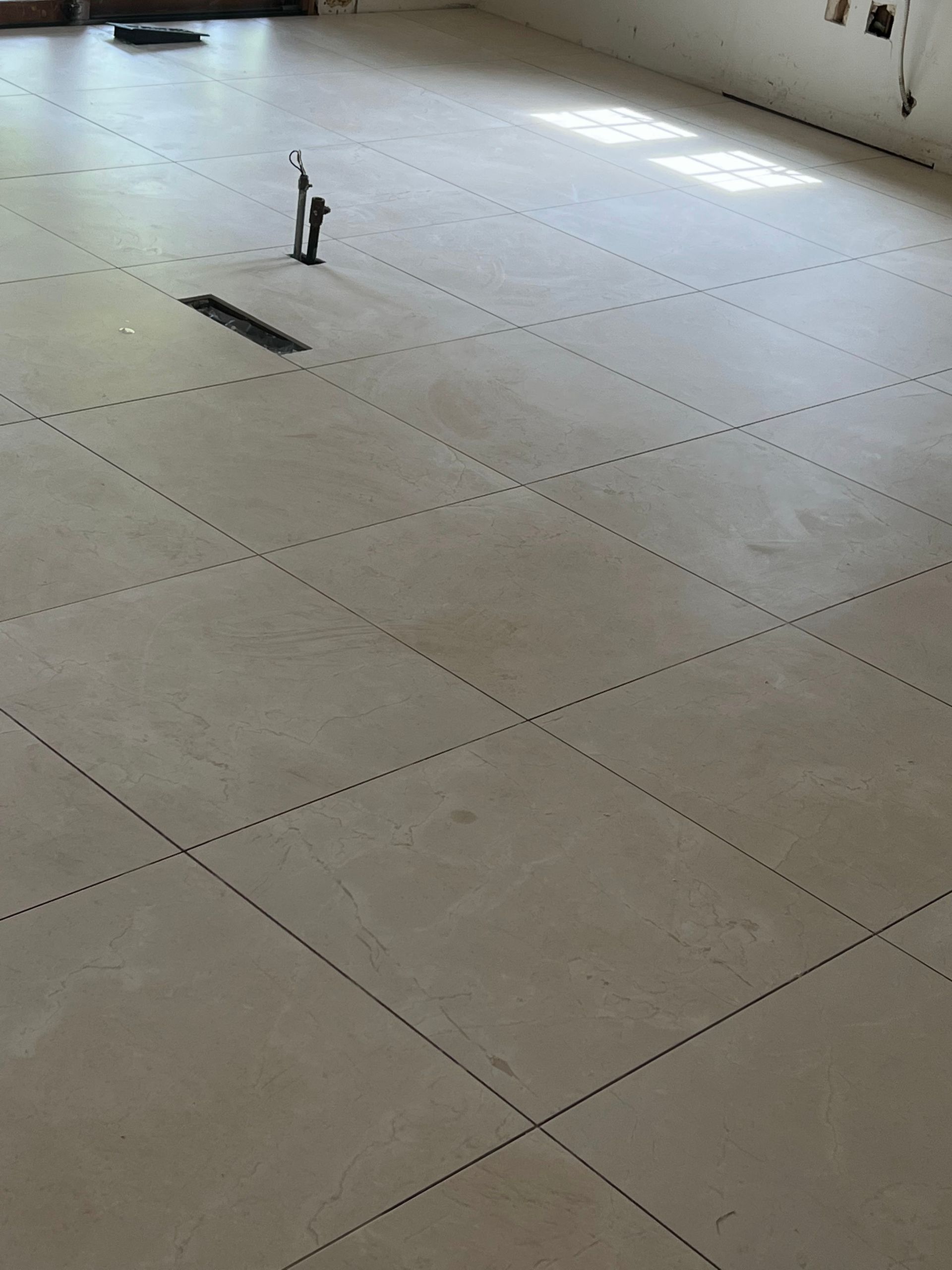 Empty tiled floor with a small upright object near the center and a dark mark nearby.