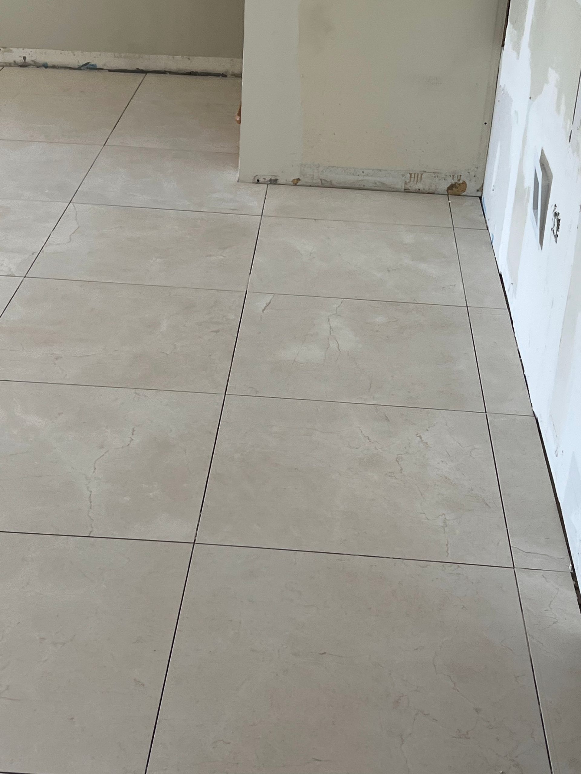 Empty tiled floor in a beige room corner with dotted grid lines.