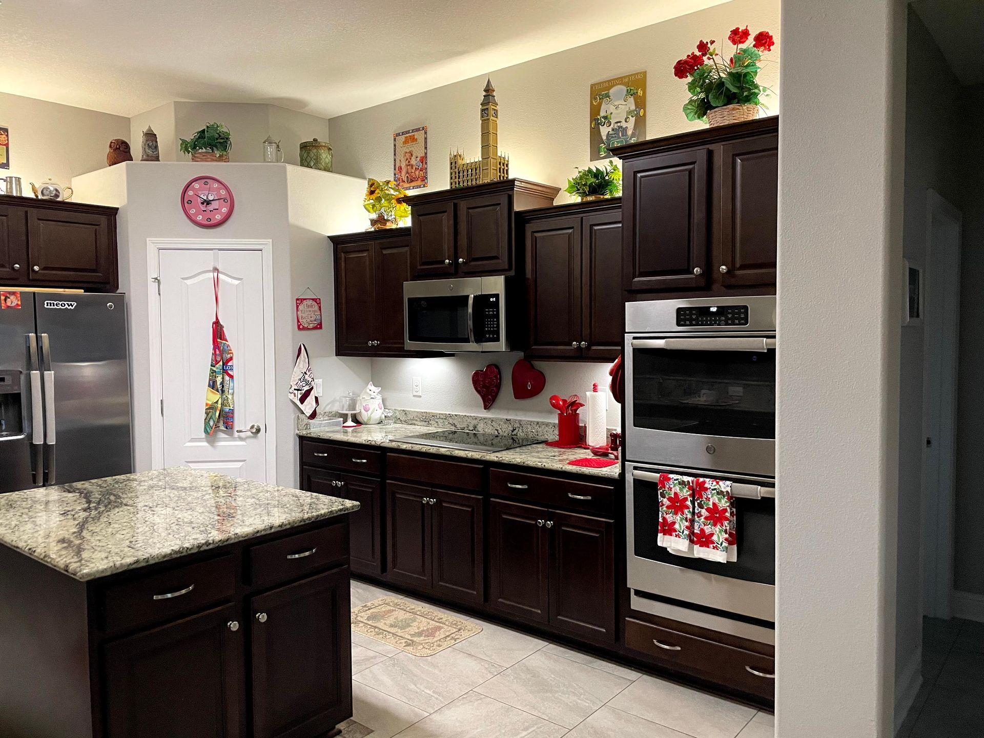 Modern kitchen with dark cabinets, stainless appliances, and a white refrigerator with magnets