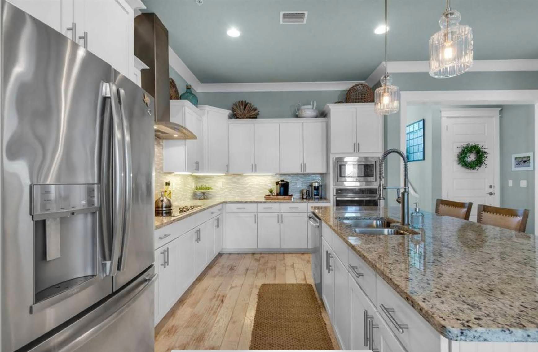 Bright modern kitchen with white cabinets, stainless steel appliances, and a granite island counter