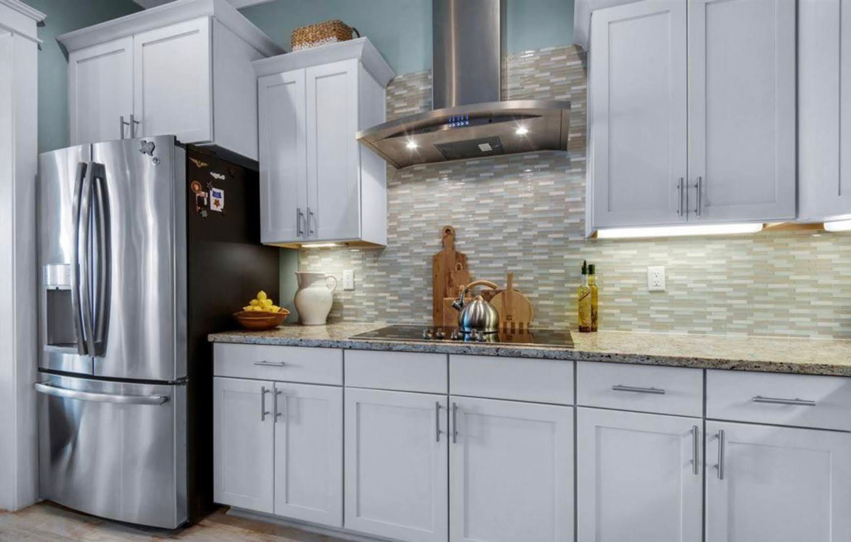 Modern kitchen with light gray cabinets, stainless steel appliances, and tile backsplash