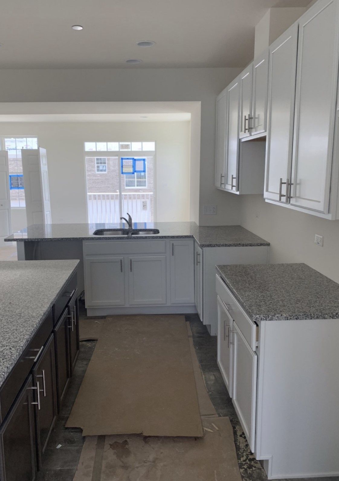 Modern kitchen with white cabinets, granite counters, and a large window at the far end.