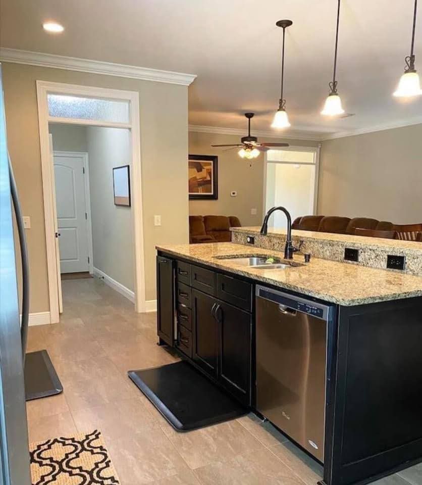 Modern kitchen with black island, granite countertop, pendant lights, and adjacent dining area.