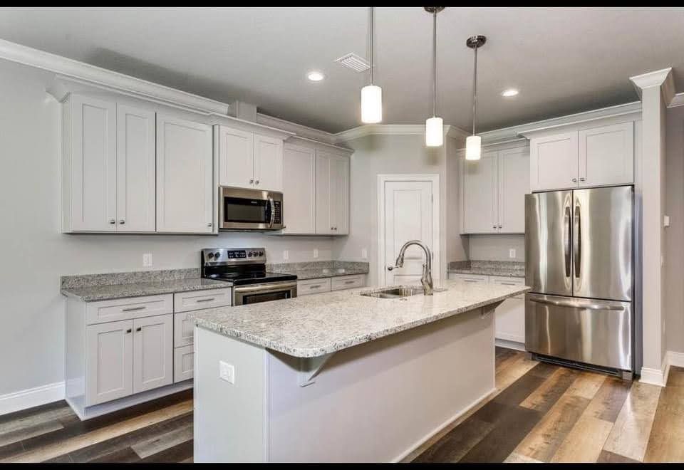 Modern kitchen with white cabinets, granite island, stainless appliances, and pendant lights