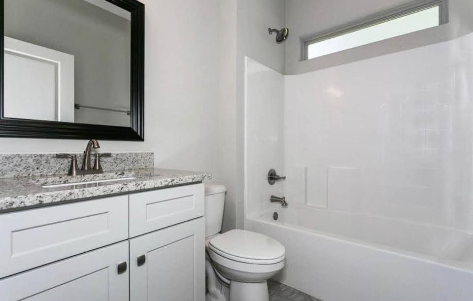 Modern bathroom with vanity, mirror, toilet, and white tub-shower combo