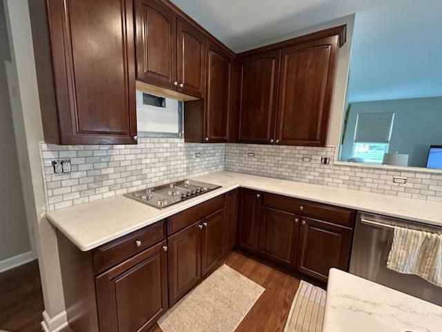 L-shaped kitchen with dark wood cabinets, white countertops, and white subway tile backsplash.