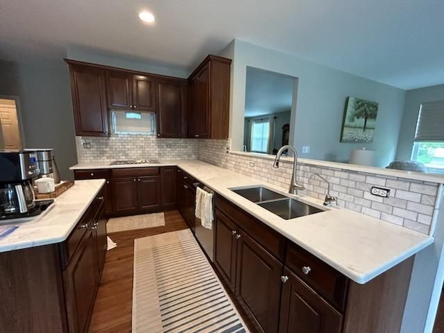Modern kitchen with dark wood cabinets, white countertops, and a large island with sink and breakfast bar.