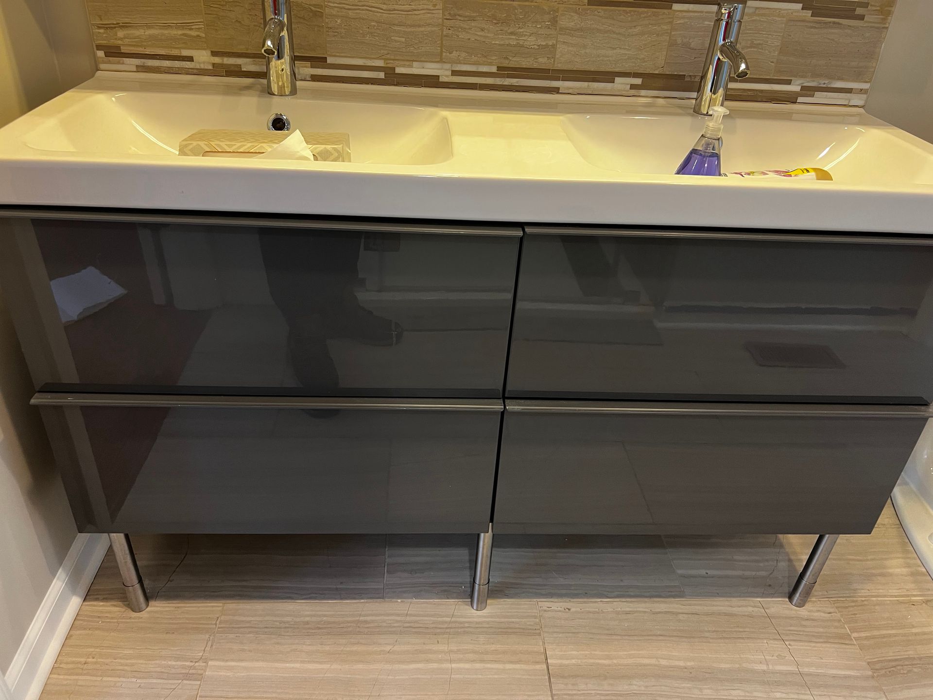 Modern bathroom vanity with dark gray drawers and a double sink countertop.