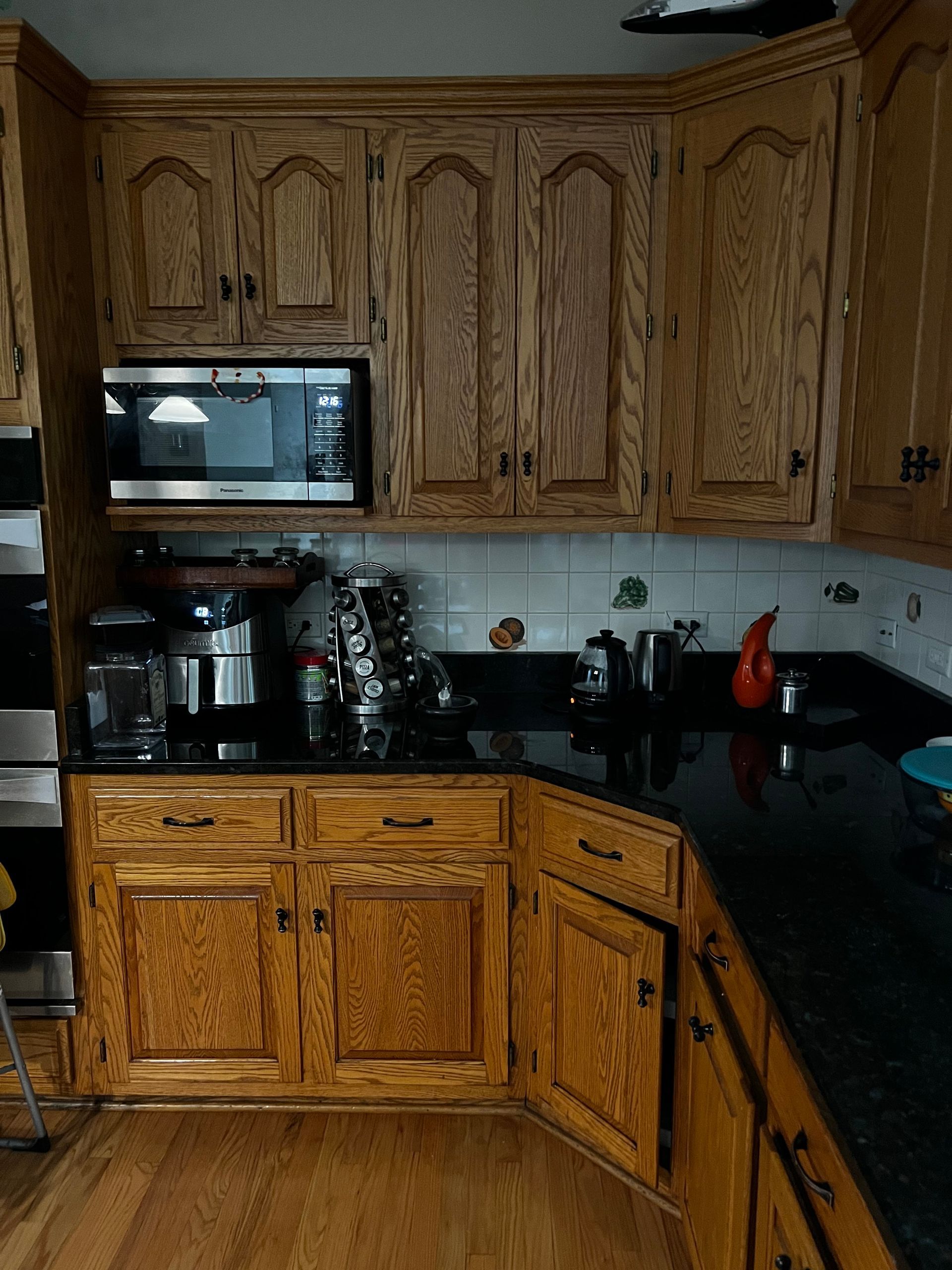 Oak kitchen with wood cabinets, black countertops, coffee maker, and microwave.