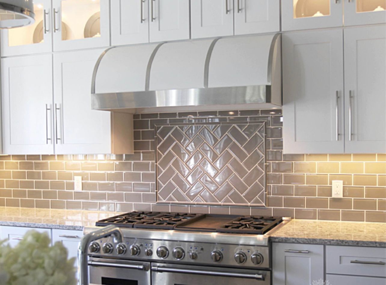 Modern kitchen with stainless steel range, gray cabinets, white subway tile, and patterned backsplash