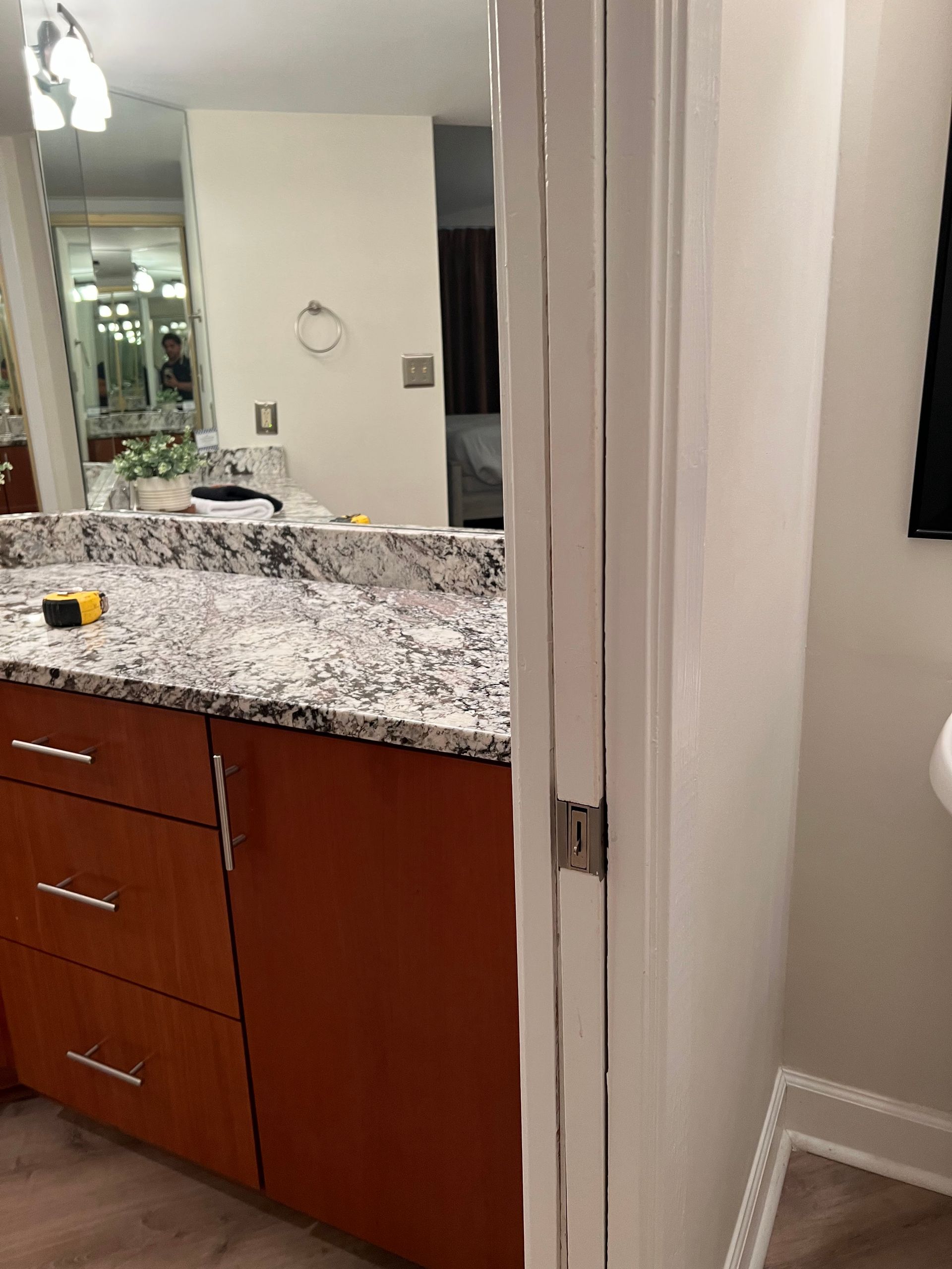 Bathroom vanity with speckled granite countertop, wood cabinets, and a mirror beside a doorway.