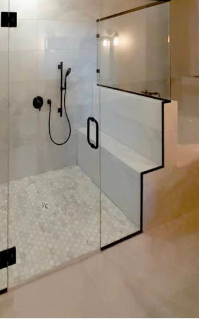 Modern glass walk-in shower with black fixtures and white tile walls and floor