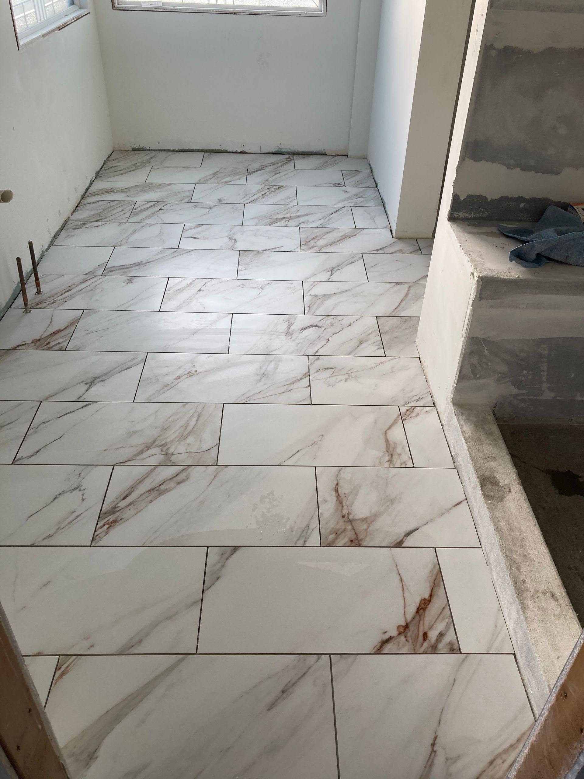 Narrow tiled room with white walls, marble-pattern floor tiles, and a built-in shelf on the right.