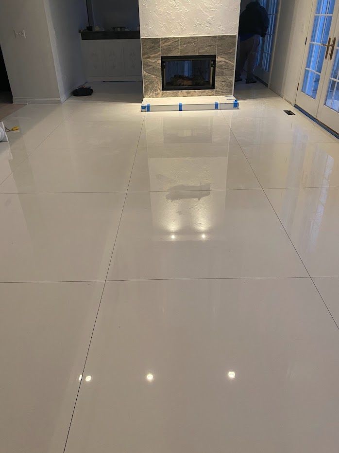 Bright living room with glossy white tile floor and a fireplace at the far wall.