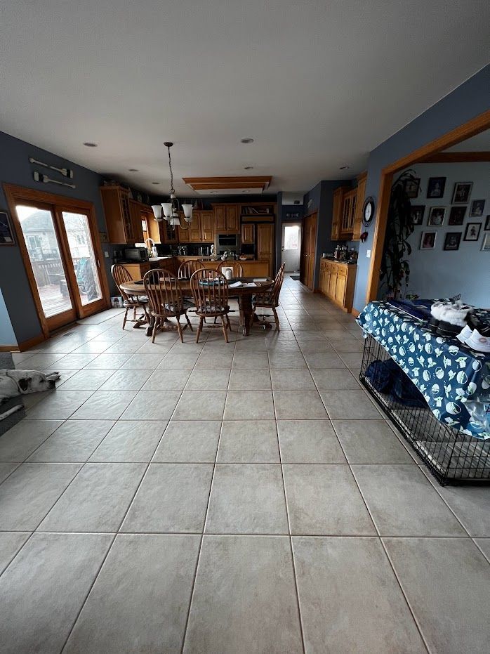 Open-concept kitchen and dining room with tiled floor, wooden table, and blue-patterned couch.
