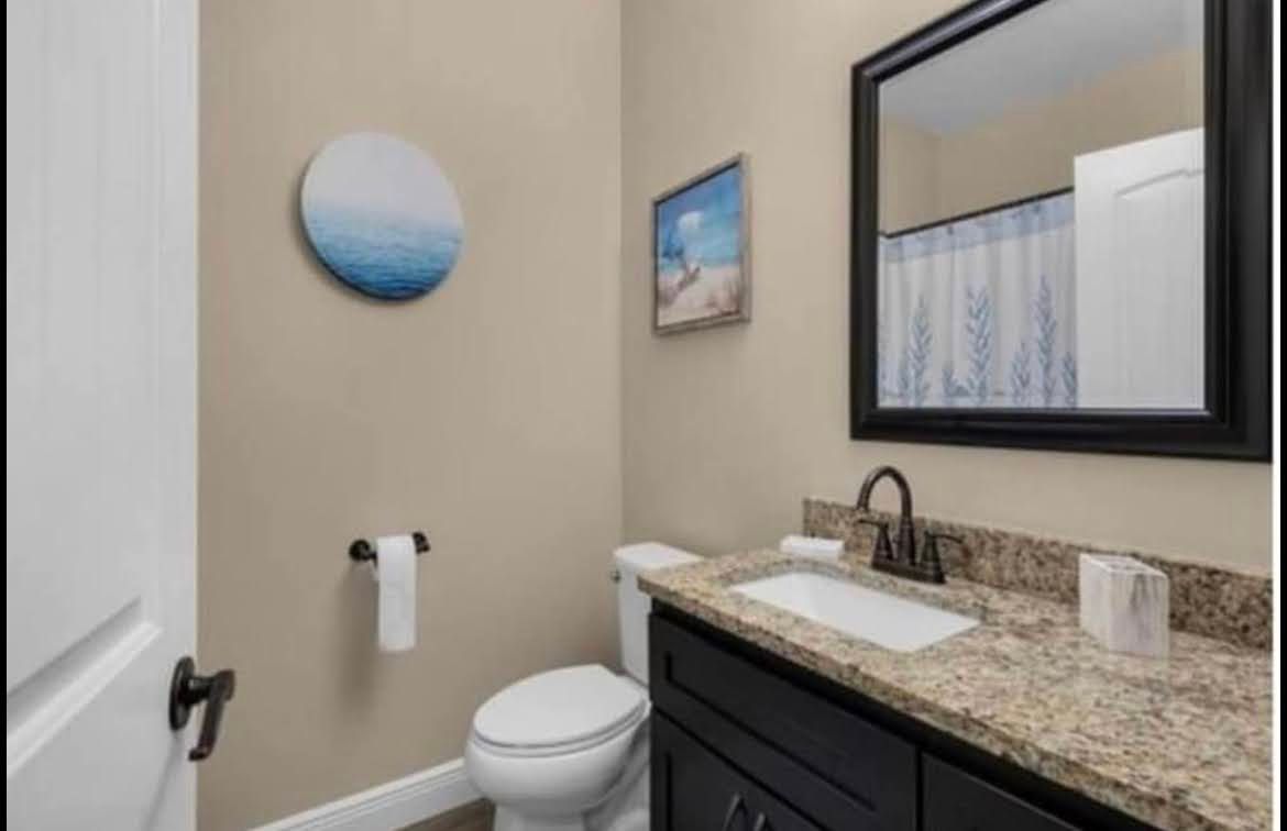 Small bathroom with a toilet, sink vanity, wall mirror, and blue towel decor