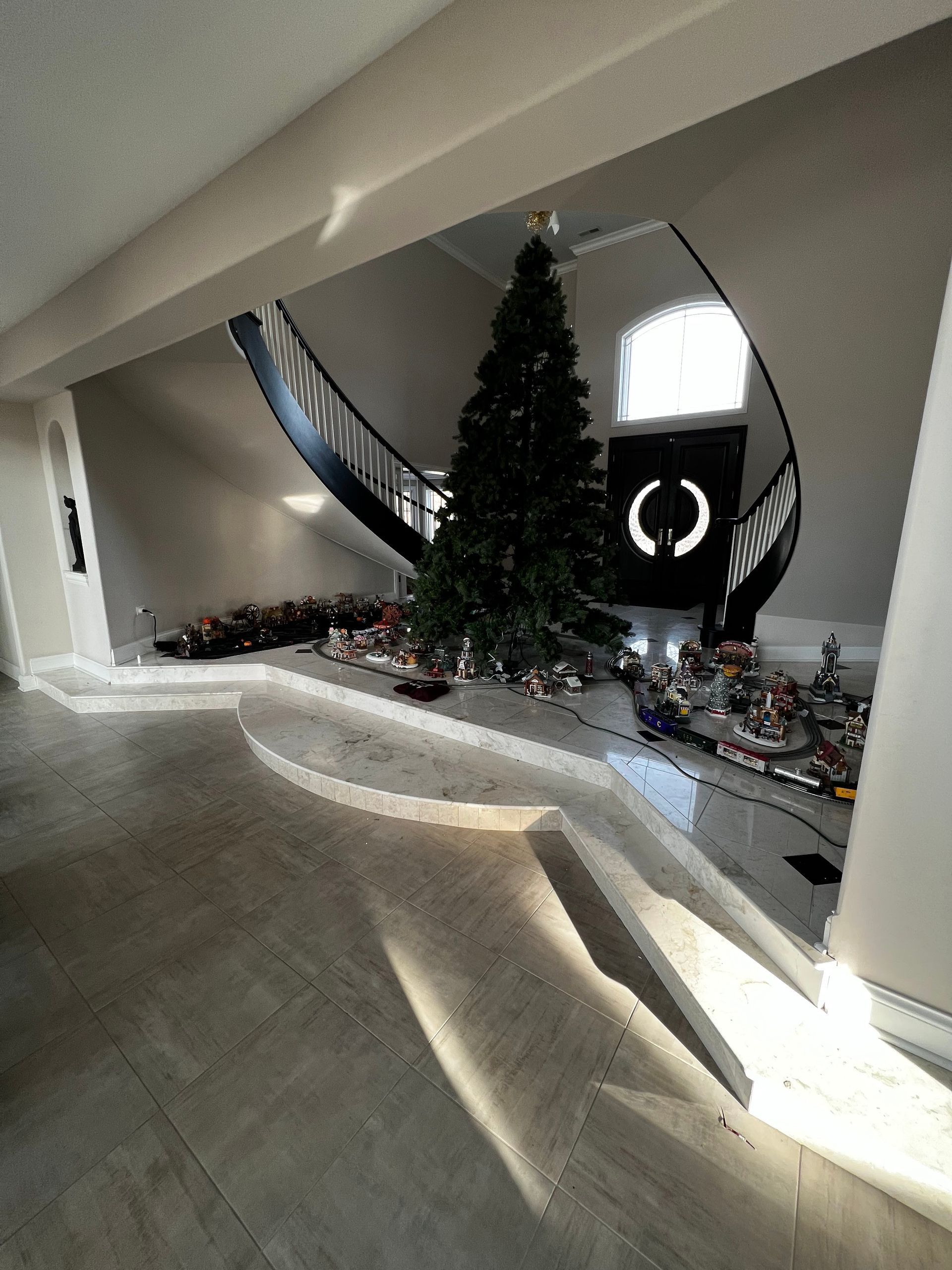 Modern living room with a tall Christmas tree, holiday decor, and bright natural light