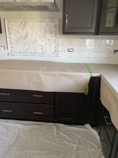 Kitchen countertop and cabinets covered in protective paper and plastic during renovation.