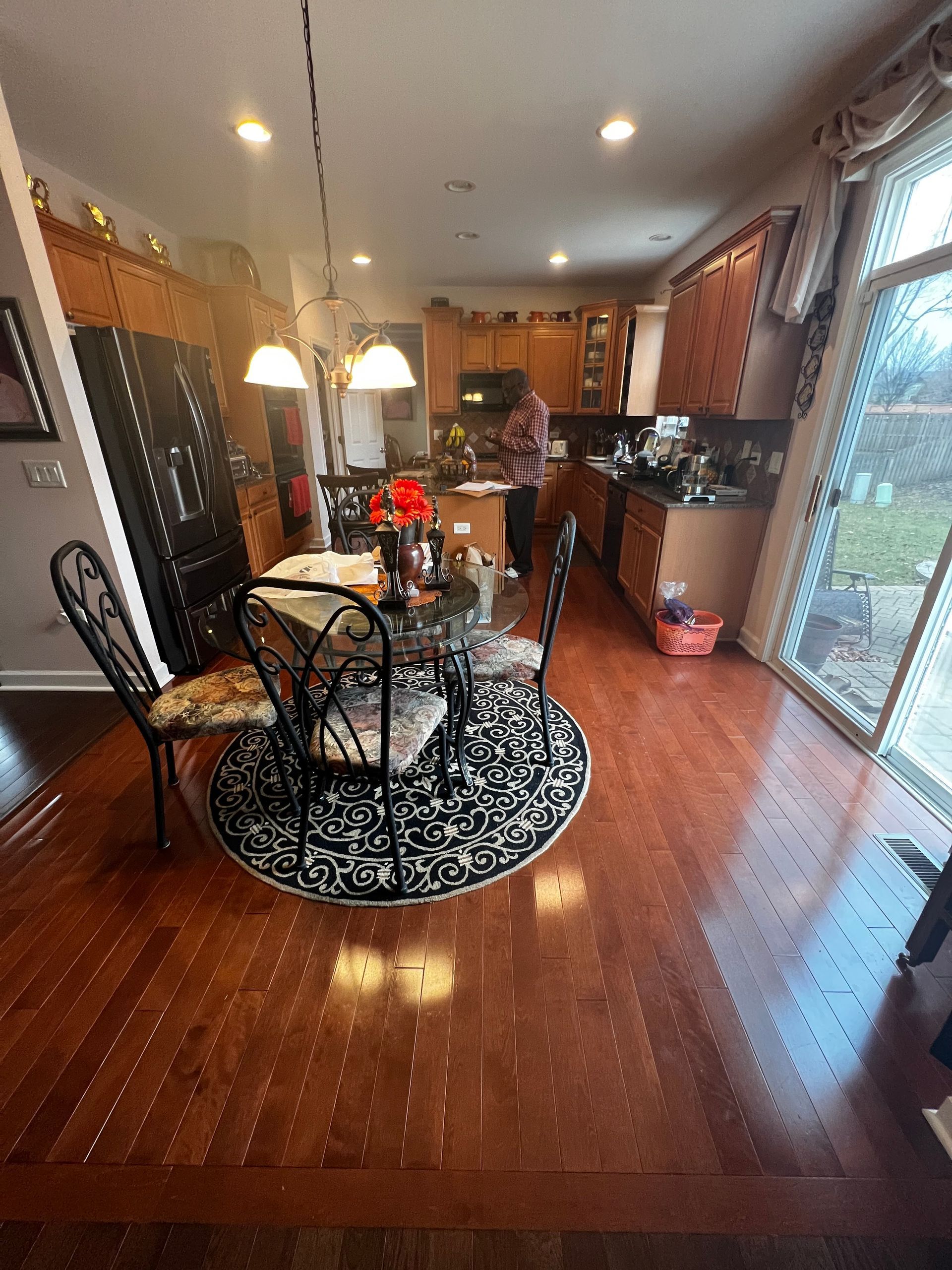 Cozy dining room with round table, chairs, pendant lights, hardwood floors, and sliding glass doors.