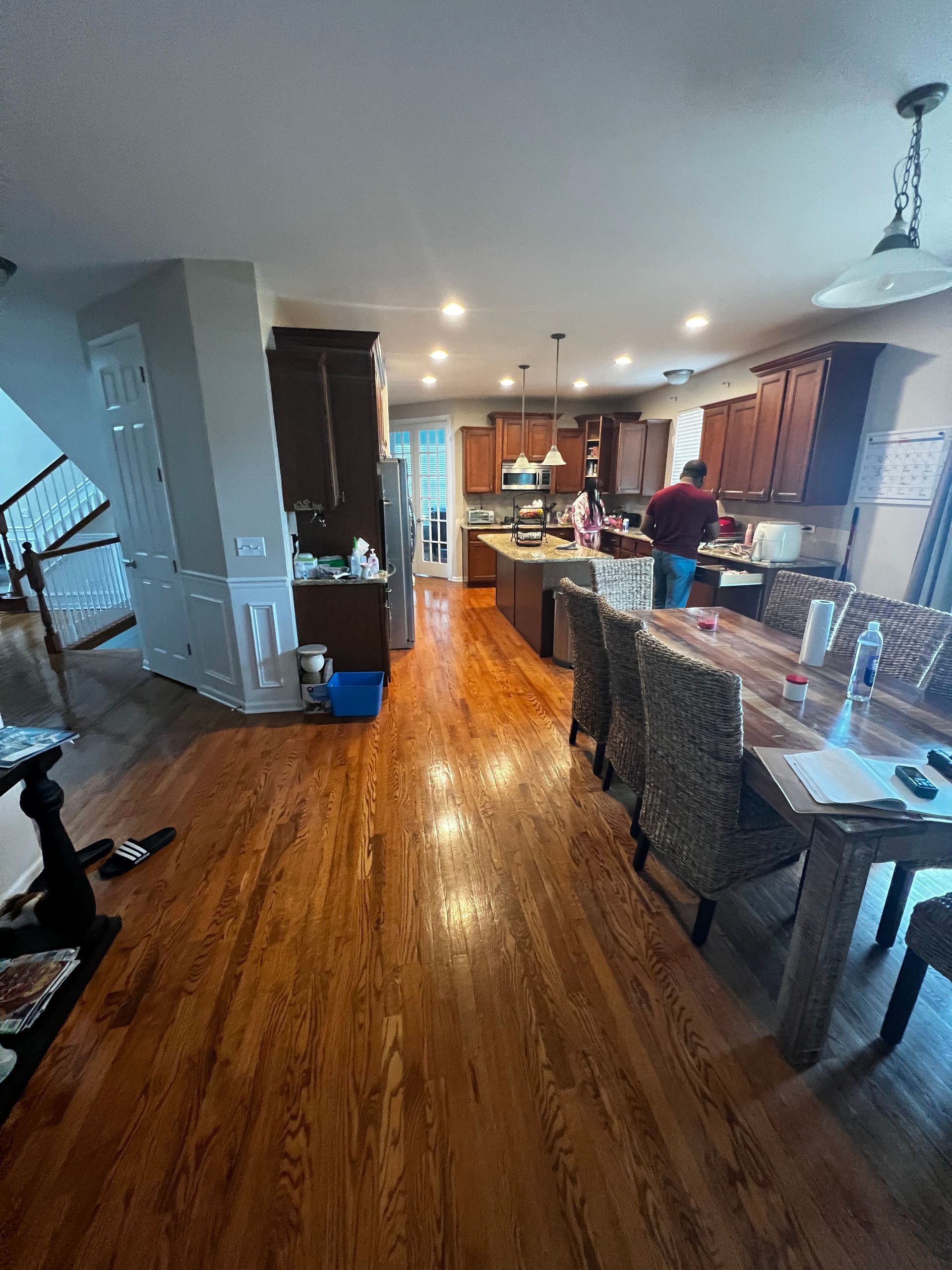 Bright kitchen and dining area with hardwood floors, island seating, and a person standing near the counter.