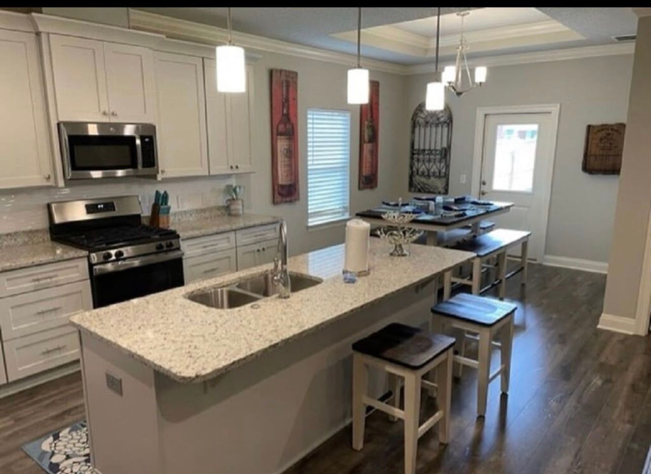 Modern kitchen with white cabinets, granite island, stainless appliances, and breakfast bar stools