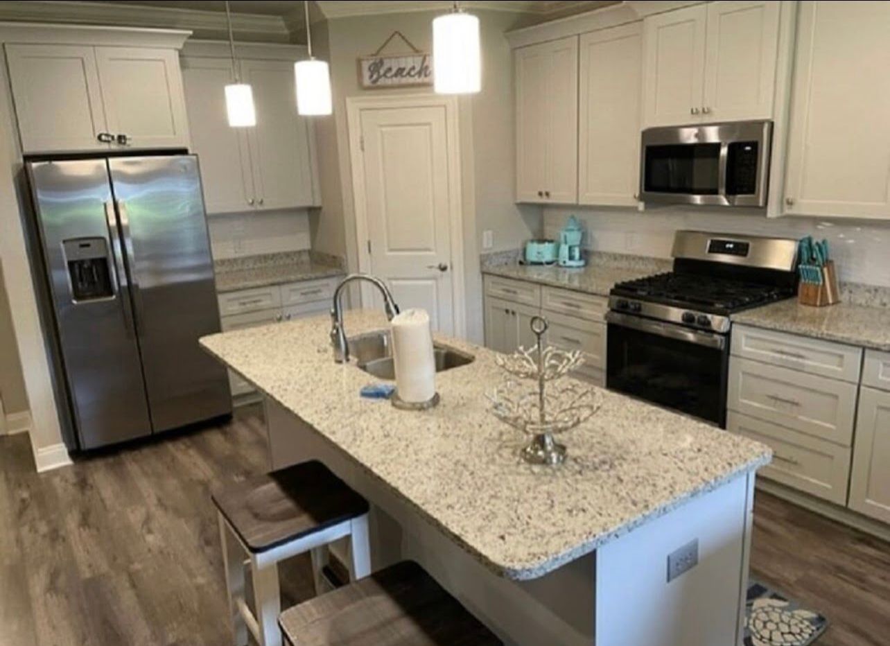Modern kitchen with stainless steel appliances, island sink, and light wood cabinets