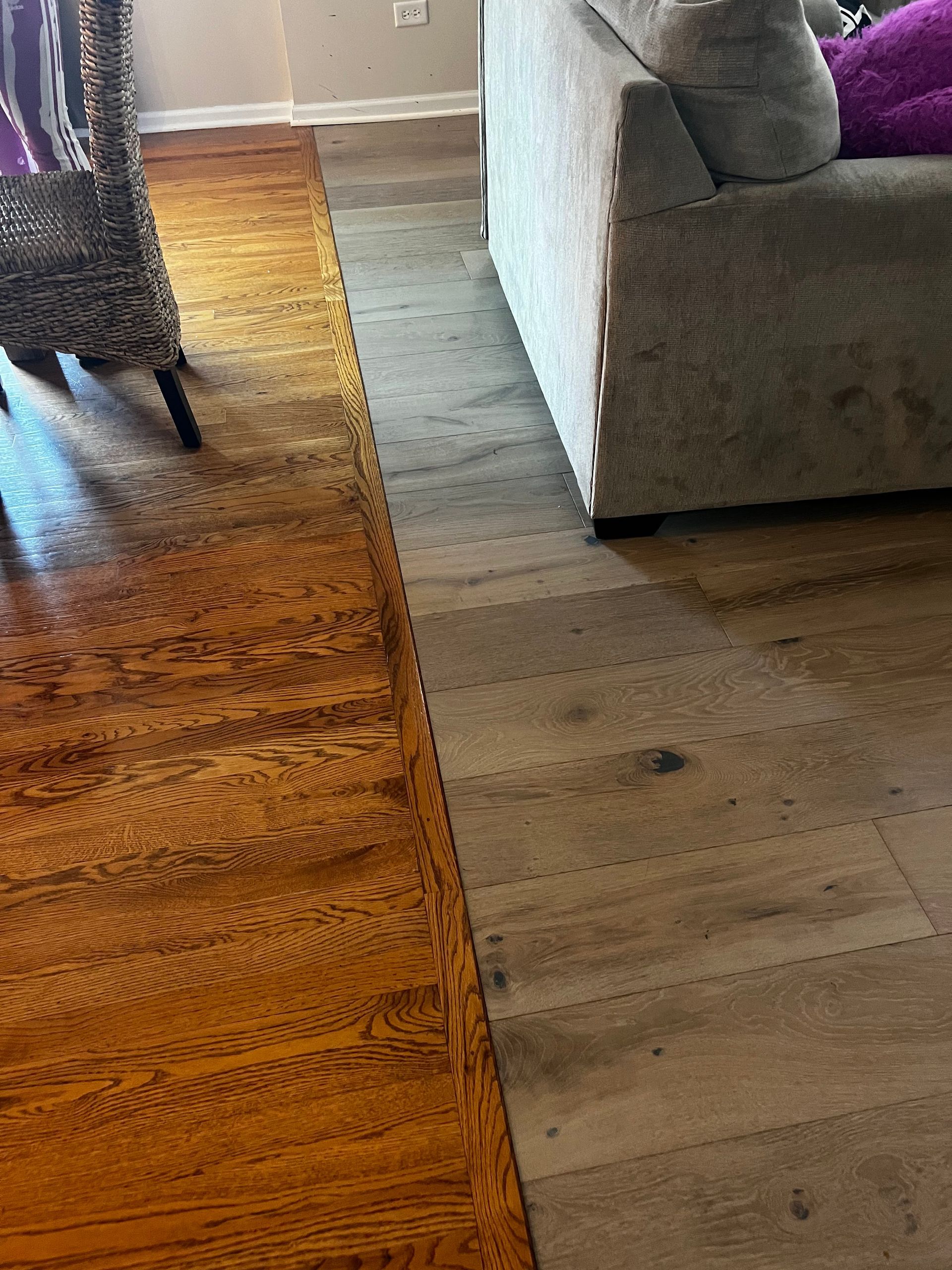 Two-tone living room floor showing wood meeting gray laminate beside a couch