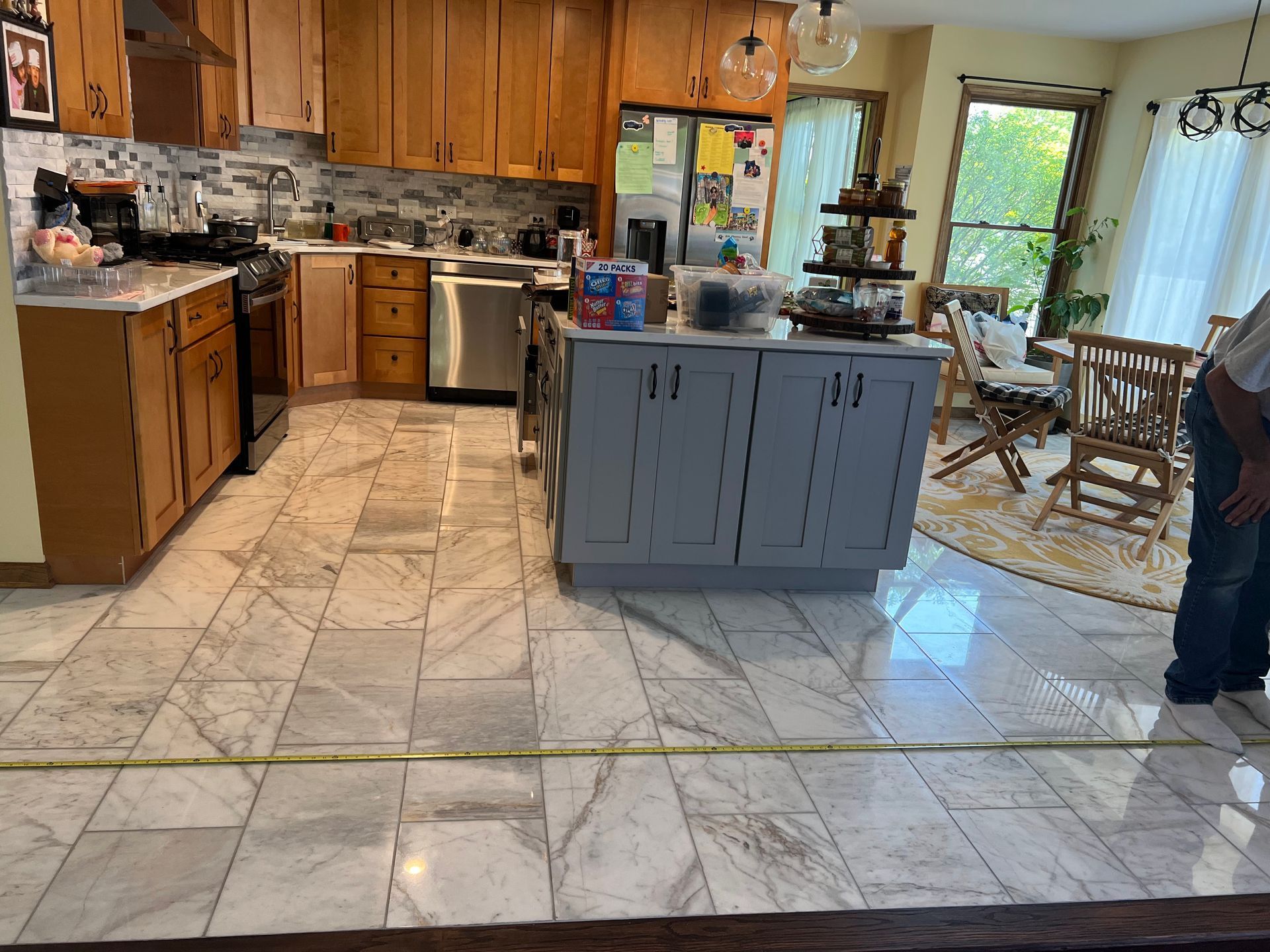 Spacious kitchen with wood cabinets, tiled floor, center island, and dining area by bright windows