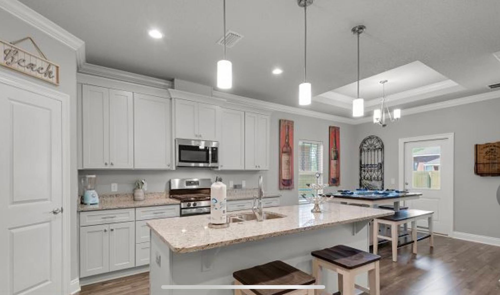 Bright modern kitchen with white cabinets, island, and pendant lights