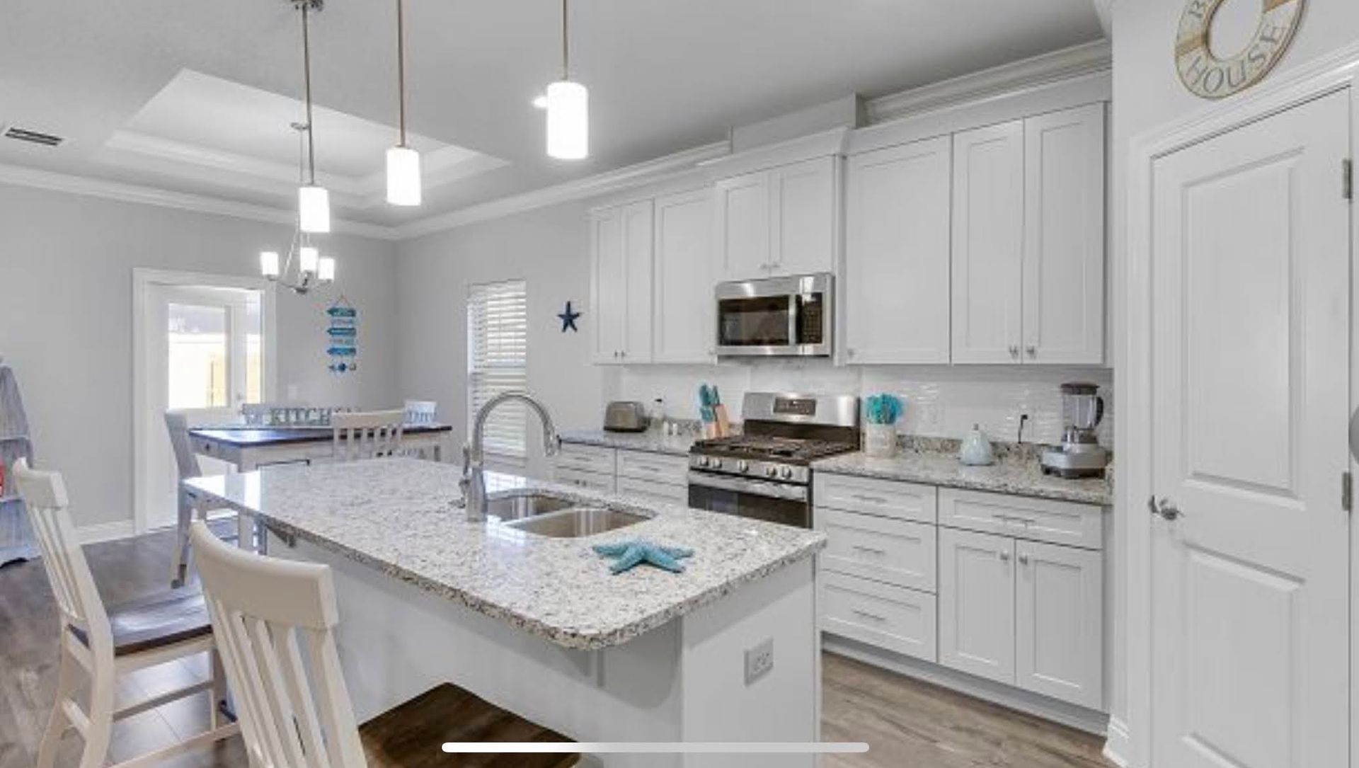 Bright modern white kitchen with island, pendant lights, and stainless steel appliances