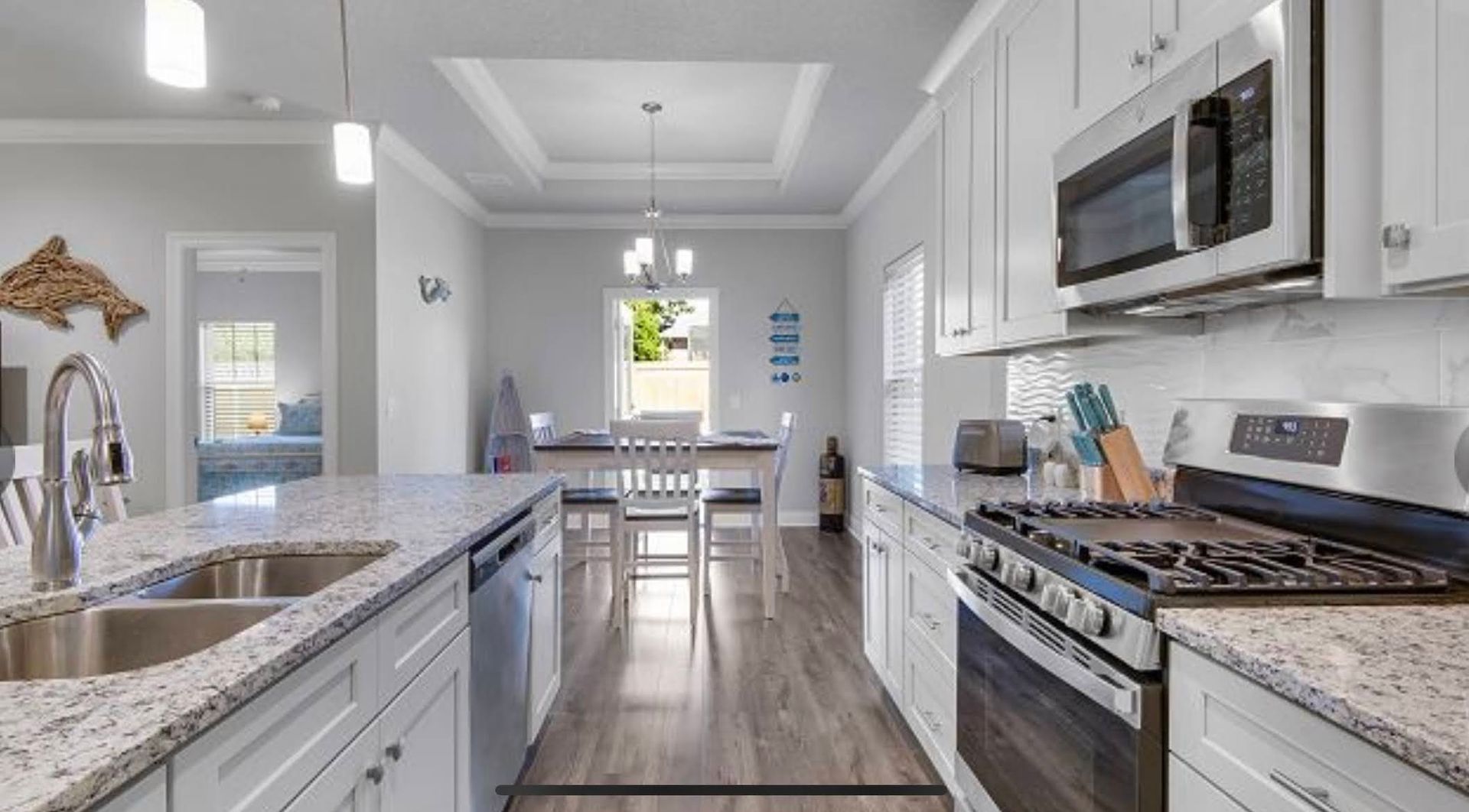 Bright white kitchen with granite counters, stainless appliances, and a dining nook by the window.