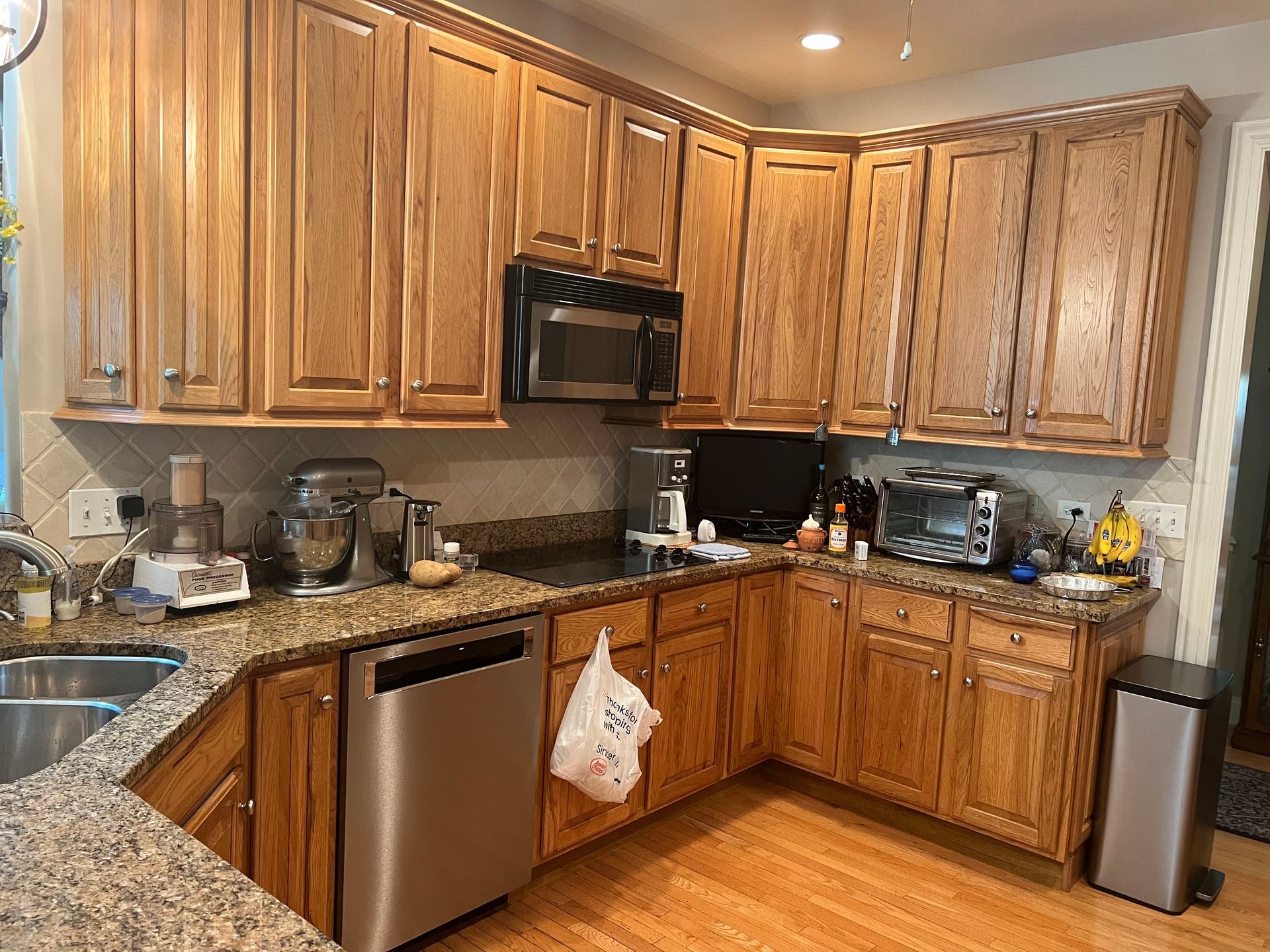 Wooden kitchen with granite countertops, stainless steel appliances, and cabinets along two walls.