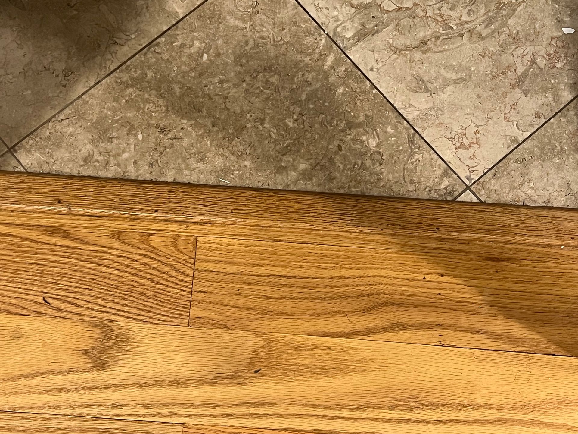 Wooden floor meeting gray stone tile floor at a diagonal seam.