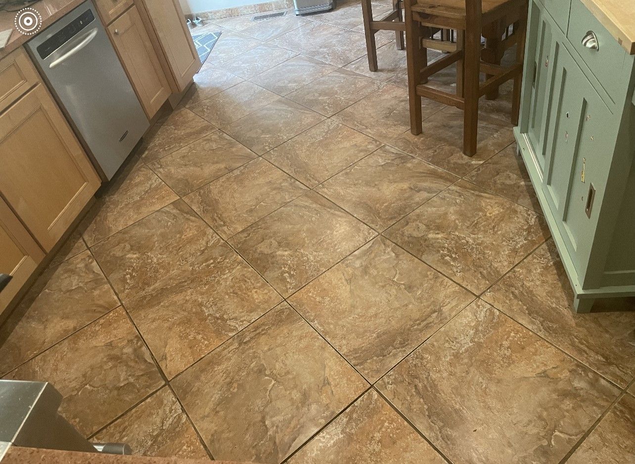 Kitchen floor with tan tile, wood cabinets, a chair, and a green pantry door