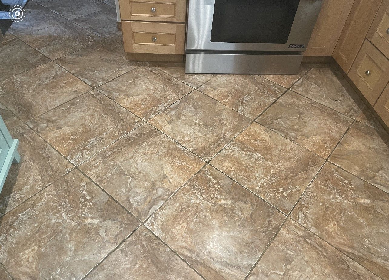 Kitchen with beige tiled floor, wooden cabinets, and stainless steel oven.