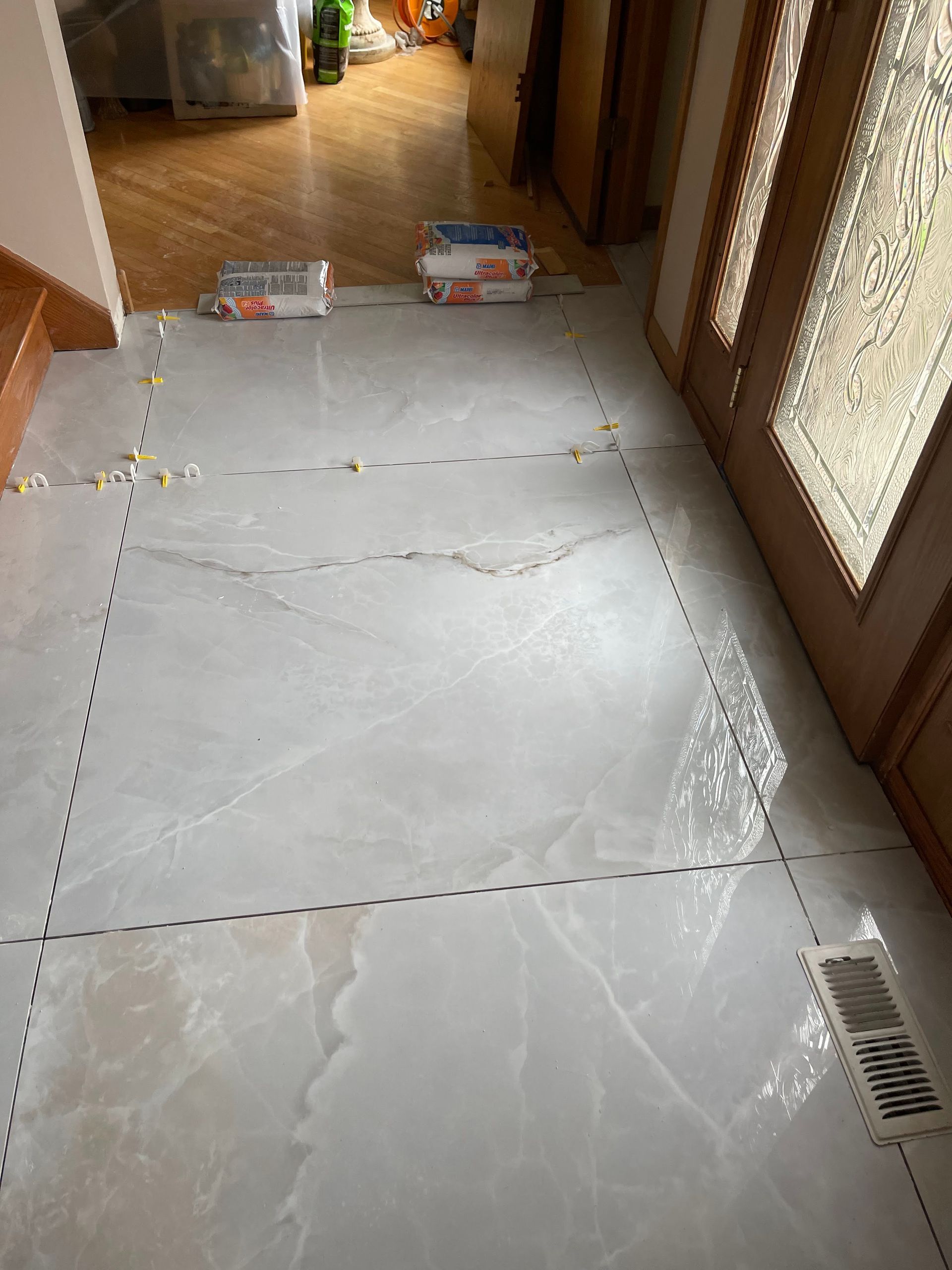 Empty hallway with large white plastic-covered floor area marked by dashed tape and a floor vent on the right.