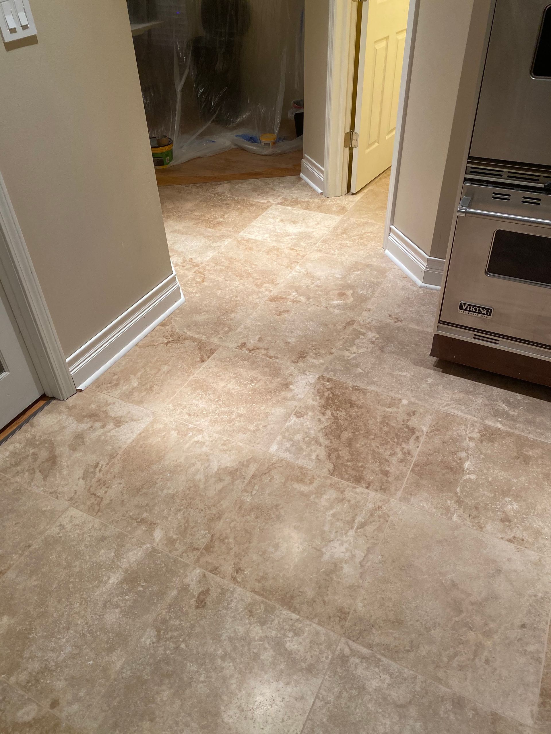 Carpeted hallway with beige walls, open doorway, and kitchen shelving on the right.