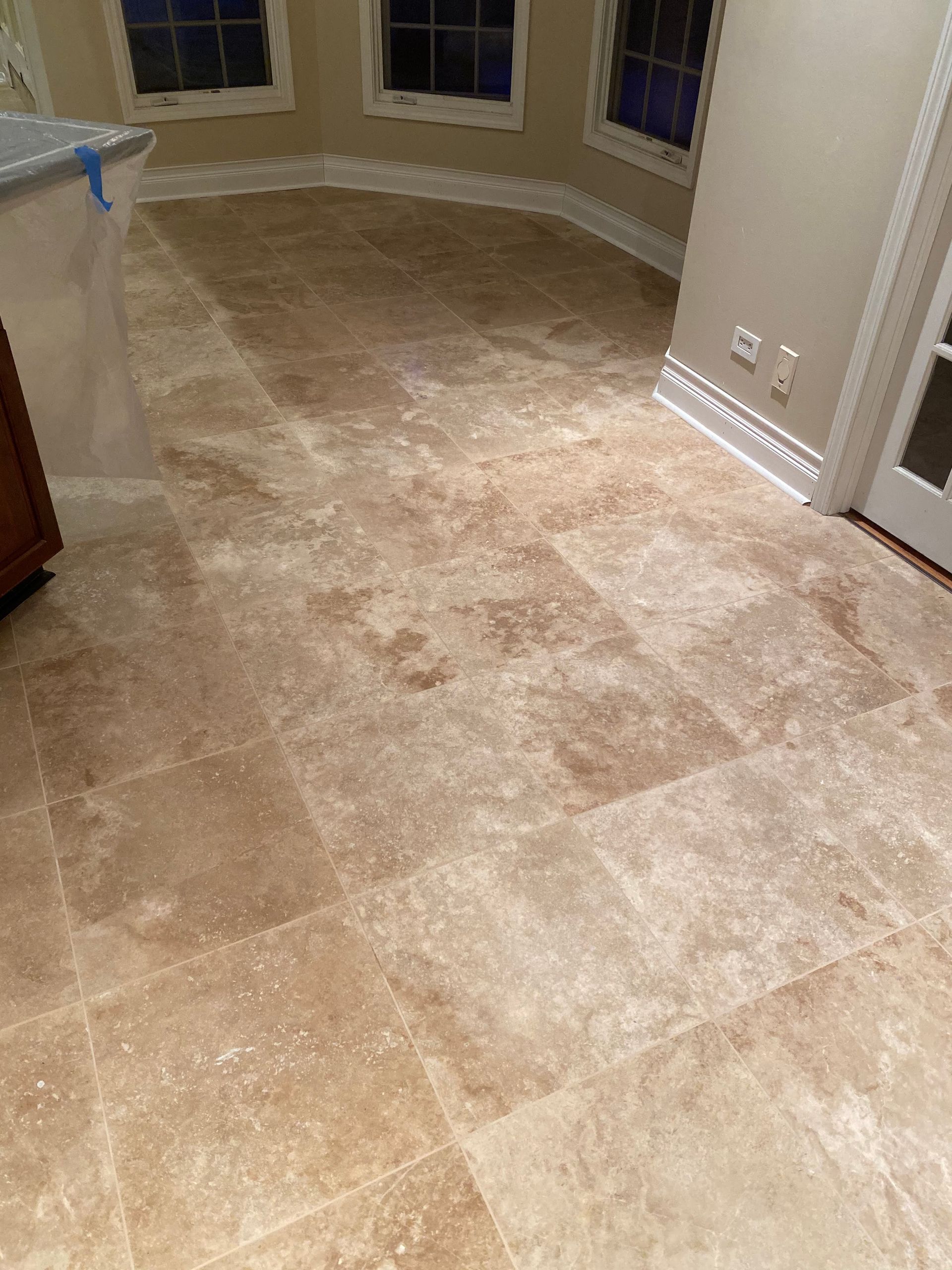 Beige tiled floor in a curved indoor room with windows and a doorway