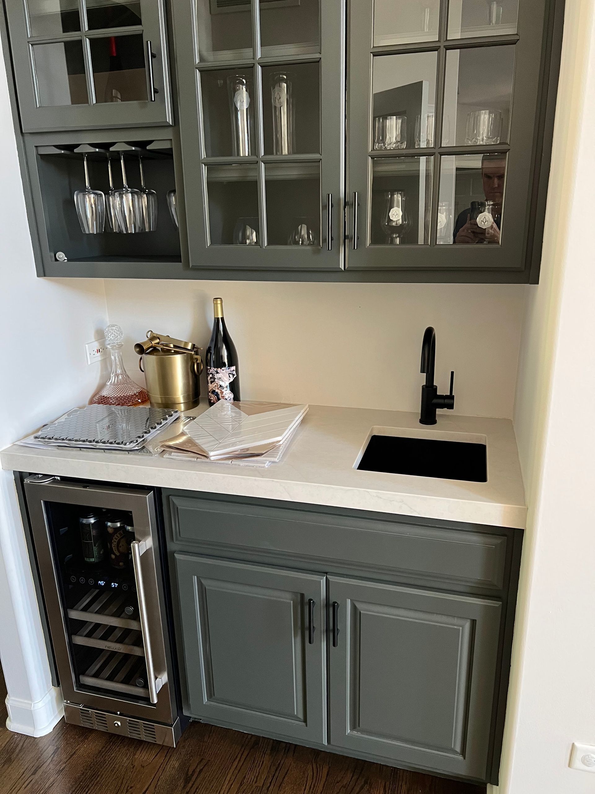 Gray kitchen wet bar with glass cabinets, sink, wine cooler, and countertop decor
