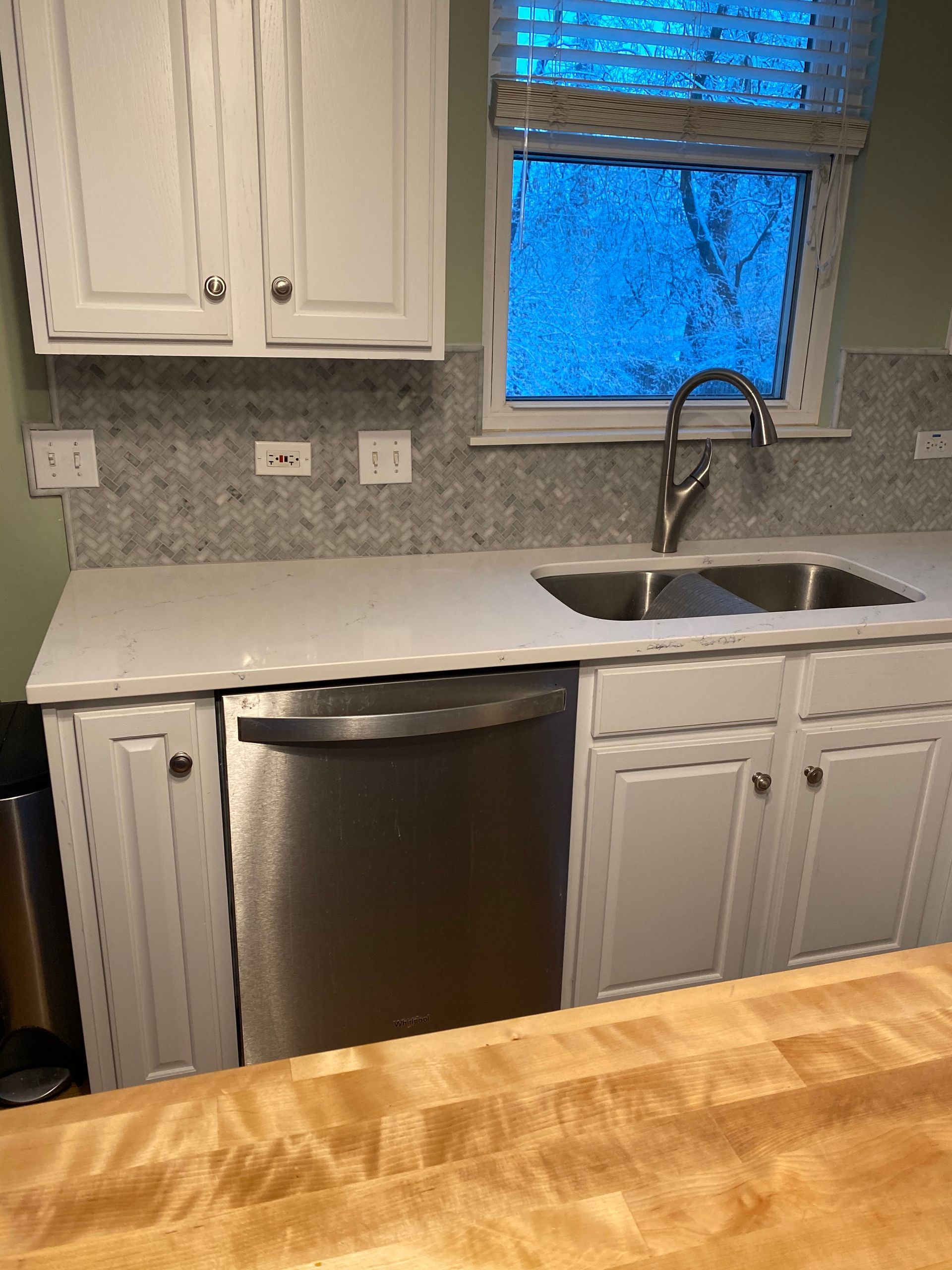 Kitchen sink area with white cabinets, stainless dishwasher, granite countertop, and window above the sink.