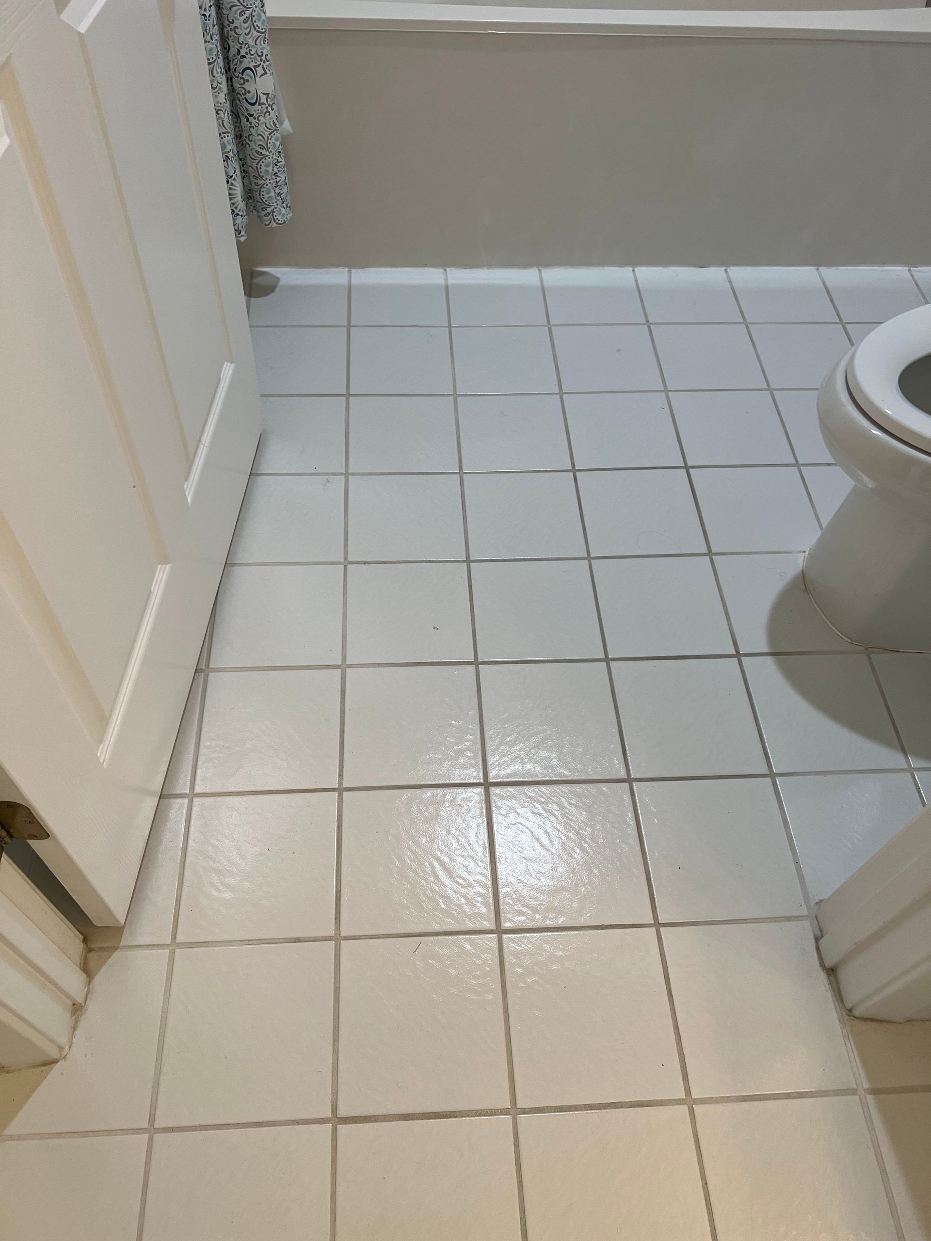 Small tiled bathroom floor with a toilet visible on the right and a cabinet on the left.