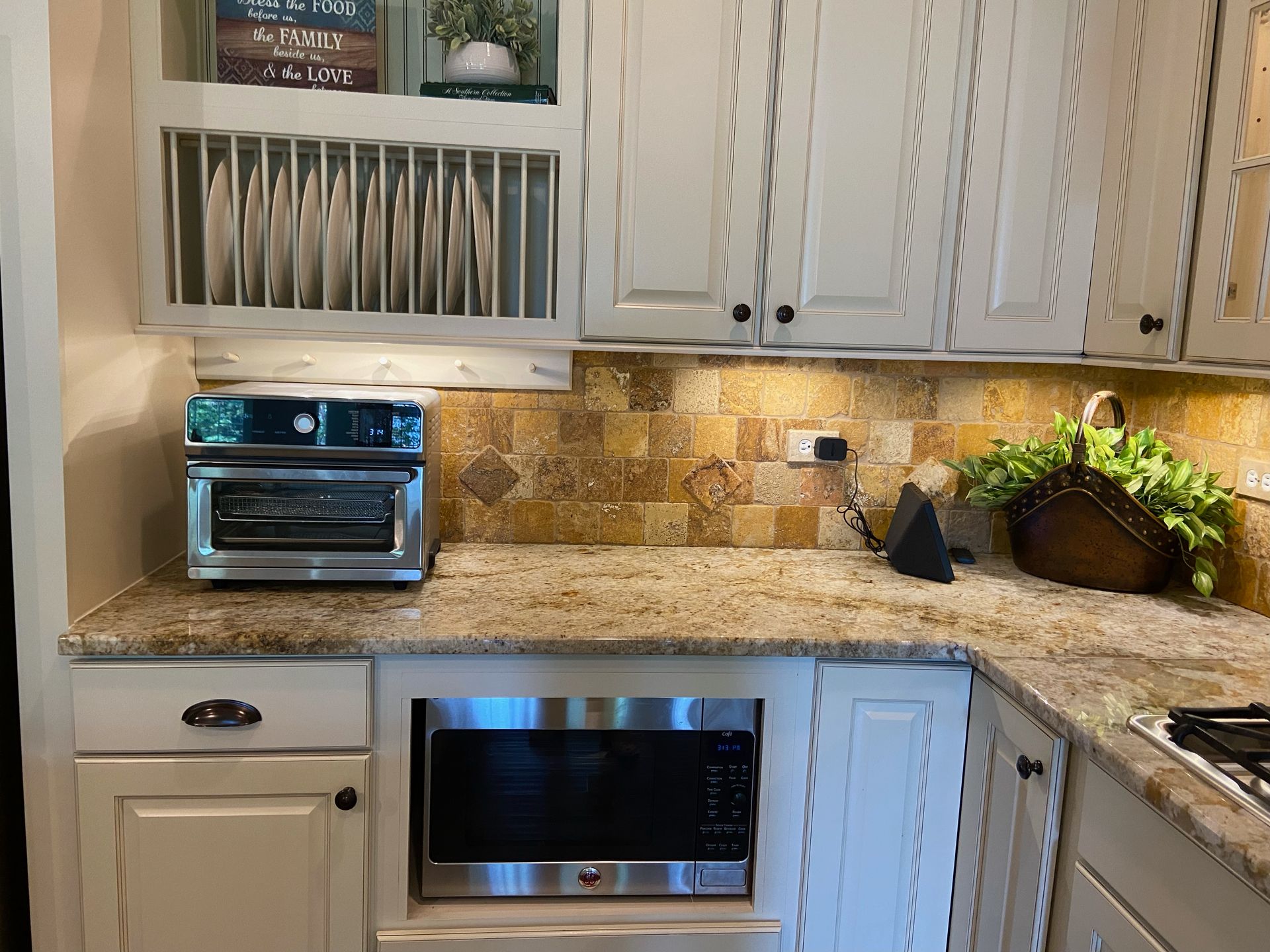 Modern kitchen with white cabinets, granite counters, backsplash, and stainless steel appliances