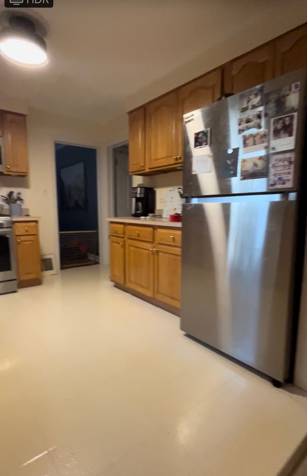 Kitchen with wooden cabinets, stainless steel refrigerator, and light-colored floor.
