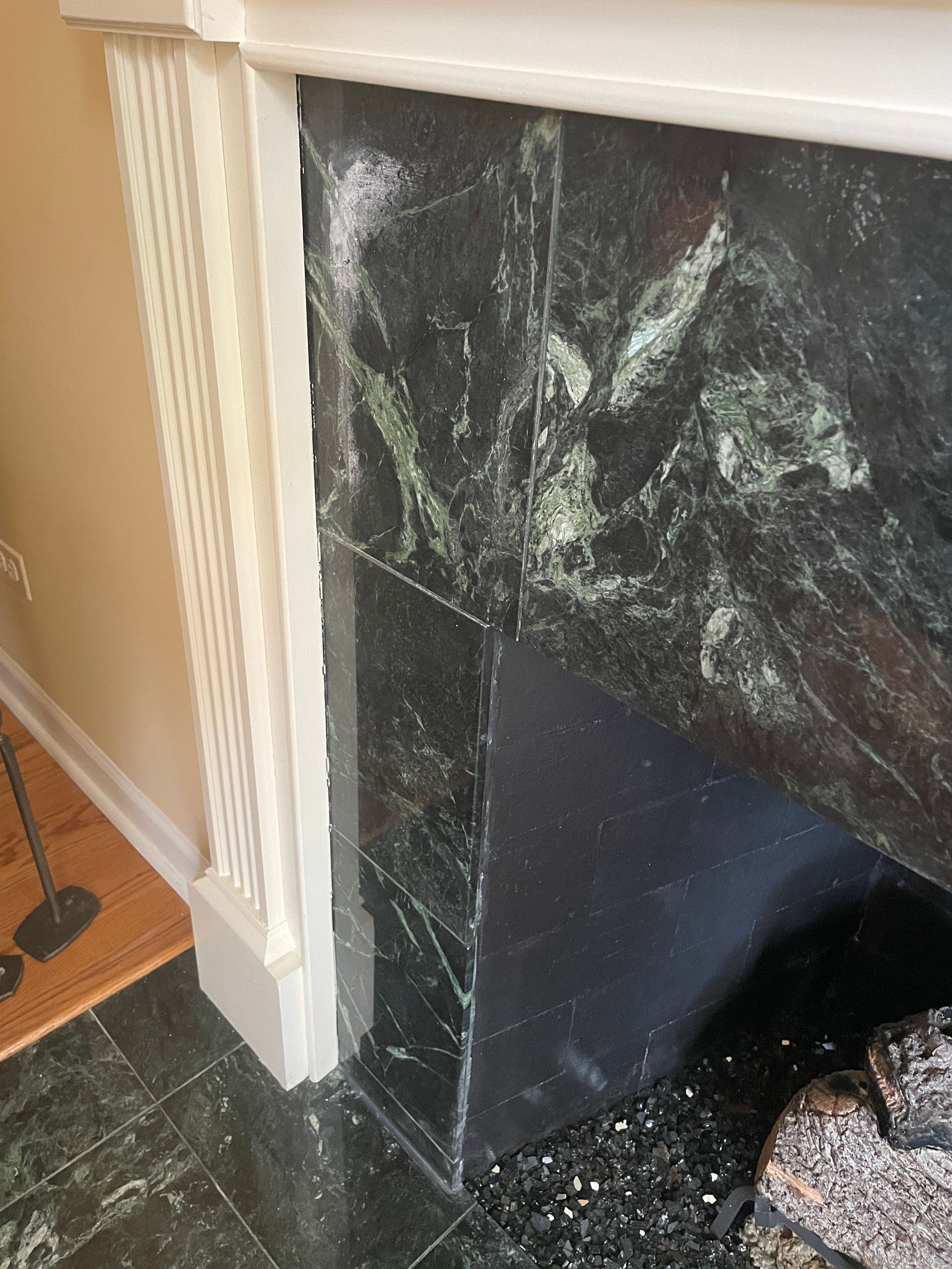 Black marble fireplace surround with white trim and a dark hearth in a room corner