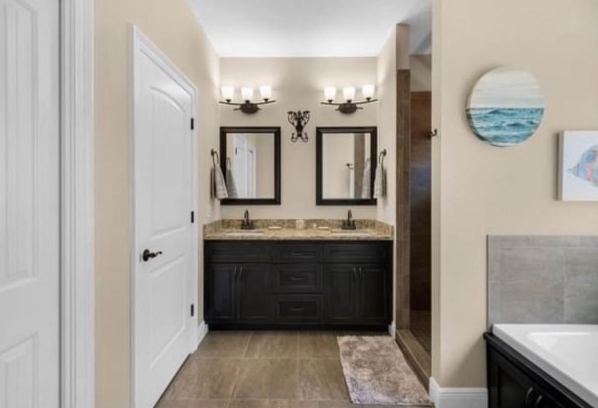 Modern bathroom vanity with double mirrors, dark cabinets, and beige walls.