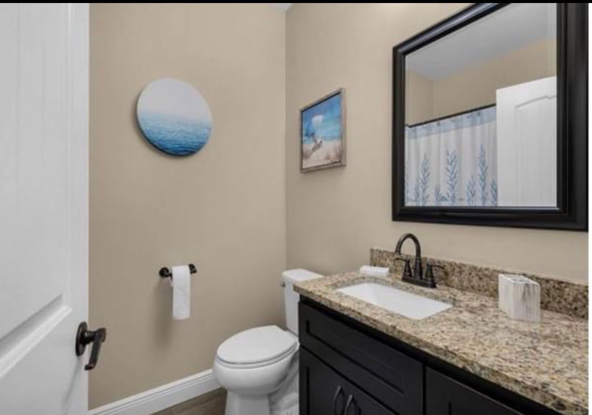 Small bathroom with vanity, sink, mirror, toilet, and wall art in neutral tones