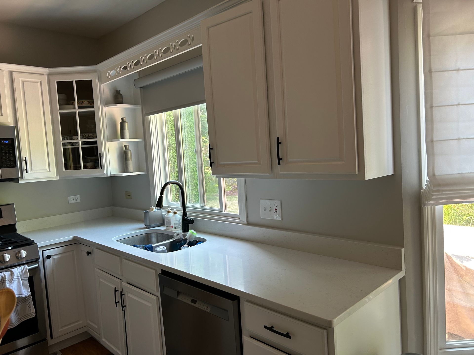 Bright kitchen with white cabinets, a sink under a window, and light countertops.