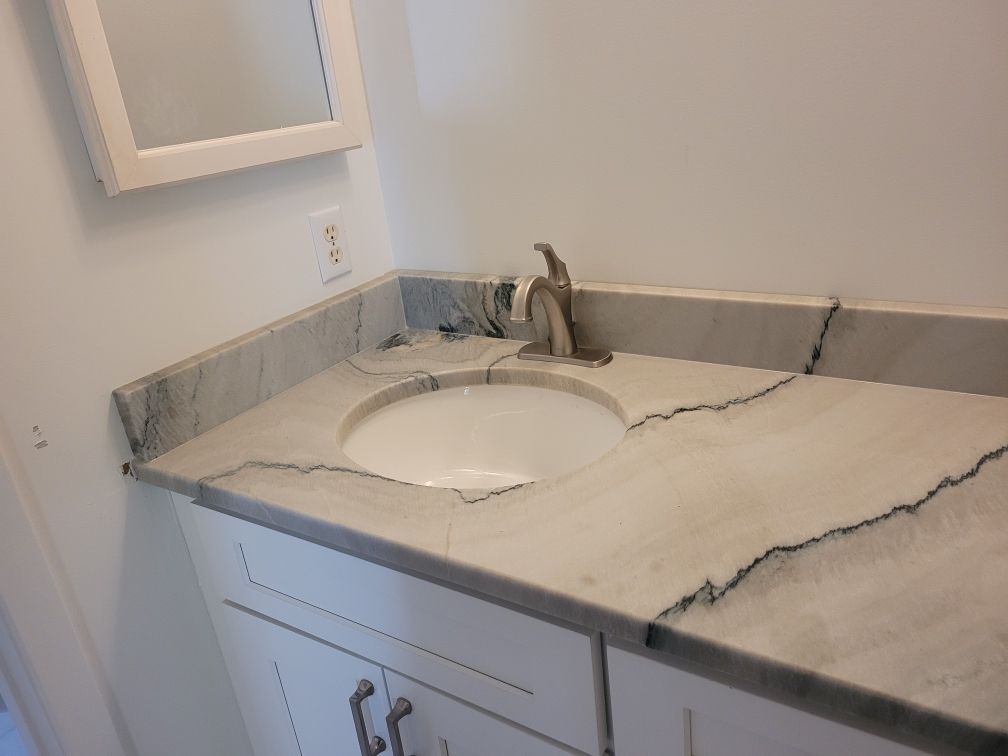 Bathroom vanity with cracked marble countertop, sink, faucet, and mirror on wall