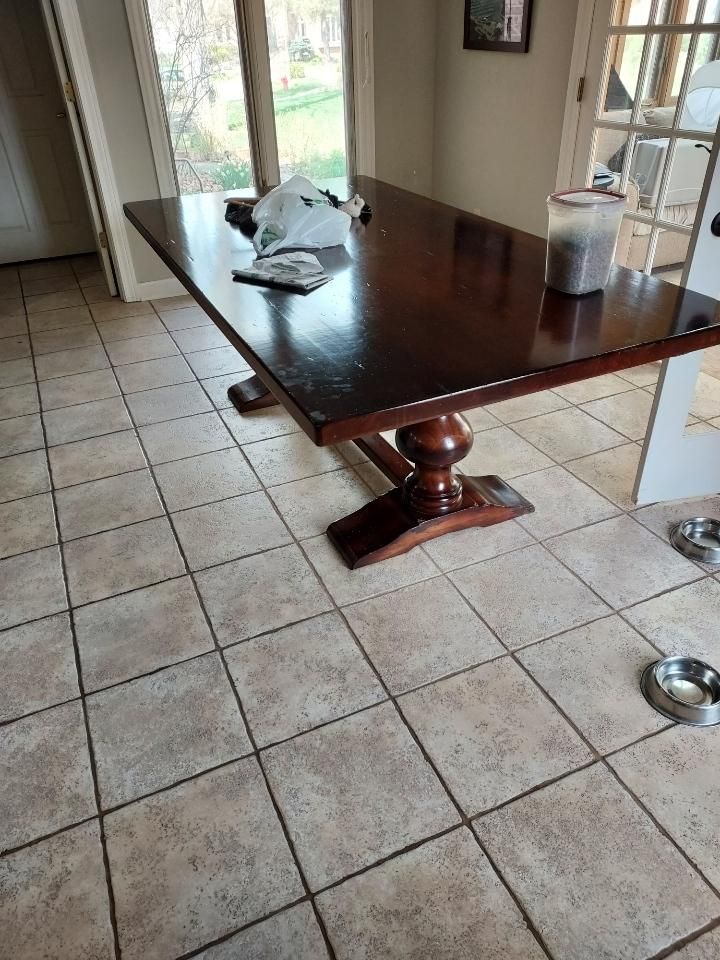 Dark wooden dining table with cloth on tiled floor beside glass doors in a kitchen area