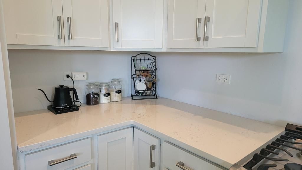 White kitchen corner with countertop, cabinets, coffee maker, and gas stove edge.